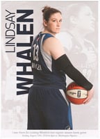 Basketball player in a gray-and-blue jersey and shorts holding a basketball with her back to the viewer, holding a basketball in her right hand.